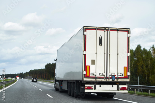Delivery and shipping of goods by semitrailer trucks. The trucks drive on the road with containers of cargo. Concept of sustainable and efficient transport system. Land logistics industry mock-up.
