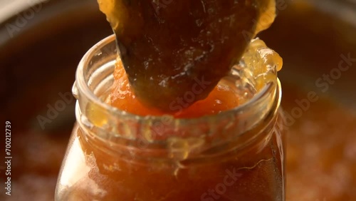 Close-up spoon picks up cooked orange jam from pan. High quality FullHD footage photo