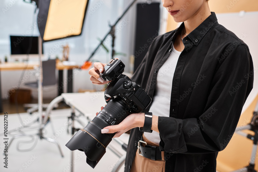 cropped view of young female photographer in everyday attire working in her studio with equipment cropped view of young female photographer in everyday attire working in her studio with equipment
