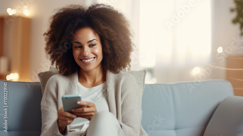 Happy woman using a smartphone while comfortably seated on a couch