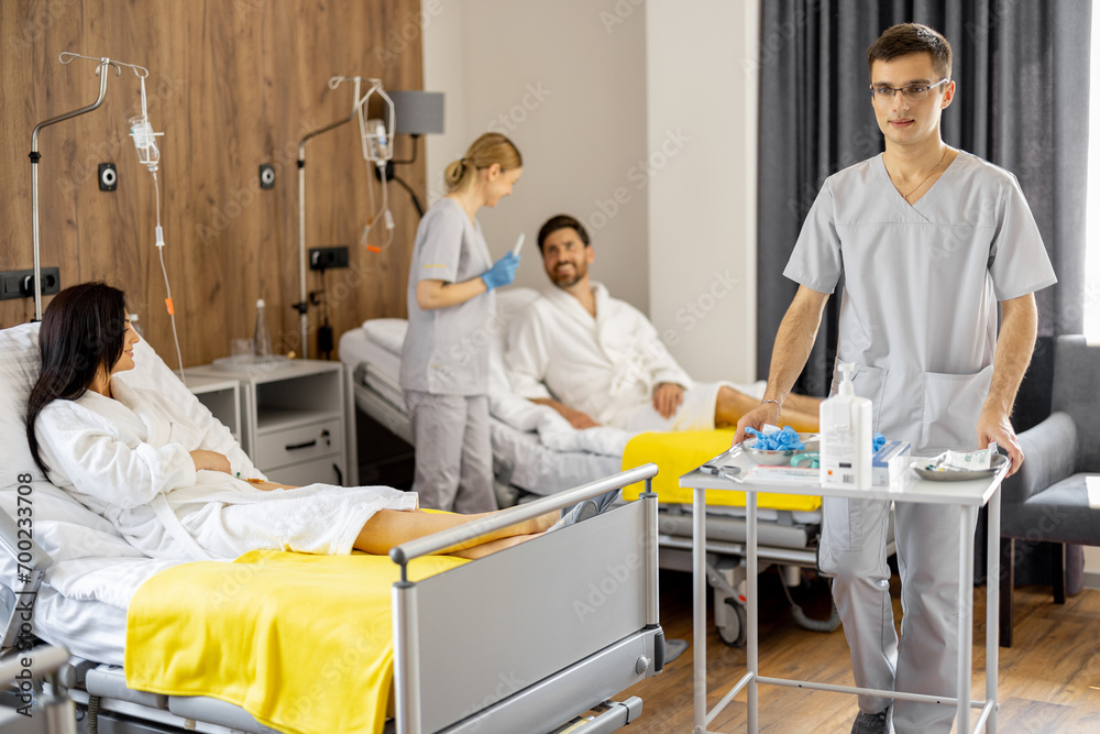 Obraz premium Nurses and patients in medical ward, nurse pushing cart with medications. Concept of nursing, support and comfortable medical suites