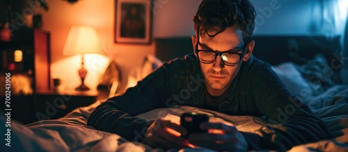 A 30-something man triumphs over a game boss on his cellphone from bed, addicted to apps. photo