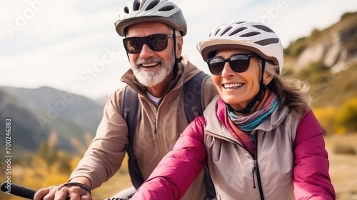 pareja de jubilados, con ropa de abrigo, cascos y gafas de sol, montando en bicicleta por la naturaleza, como parte de un viaje de aventura para personas mayores