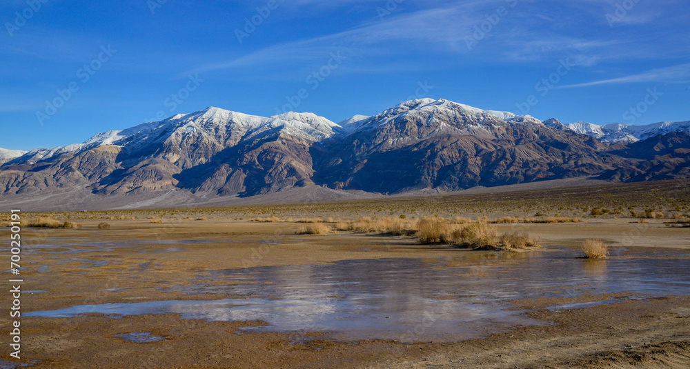 Landscape of wet clay desert in winter against the backdrop of snow-capped mountains in the Death Valley area Landscape of wet clay desert in winter against the backdrop of snow-capped mountains in the Death Valley area