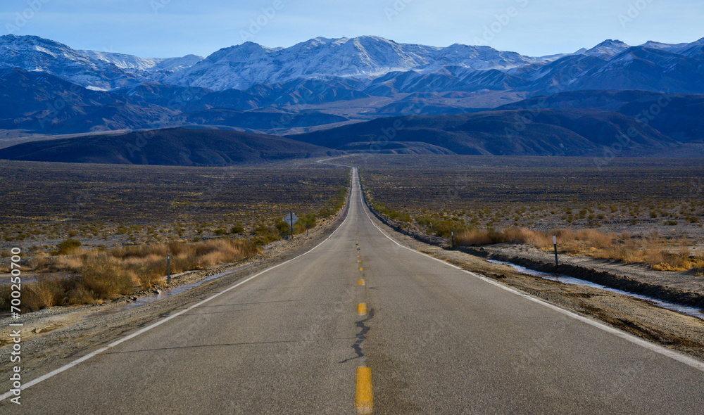 Naklejka premium Straight Road in the California desert, going into the mountains near Death Valley National Park