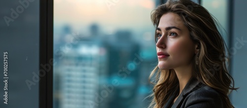 Young beautiful lady looking out panoramic window in modern consulting company office. photo