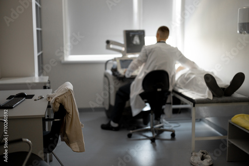 Ultrasound specialist examining male patient in medical office  wide view on medical room where the diagnostic procedure takes place