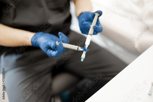 Phlebology doctor prepares special solution in syringe for sclerotherapy, close-up on syringe. Concept of medical treatment of varicose veins photo