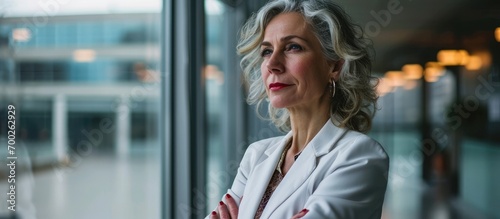 Contemplative businesswoman in her 40s, standing composedly in office with crossed arms. photo