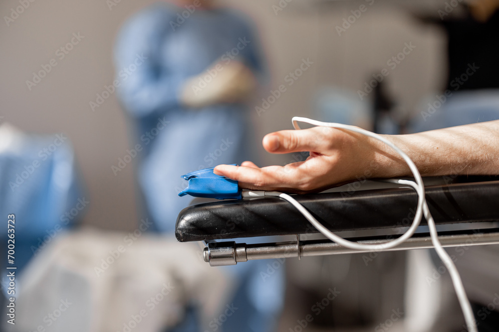 Patient's arm with a pulse oximeter lying on the operating table during