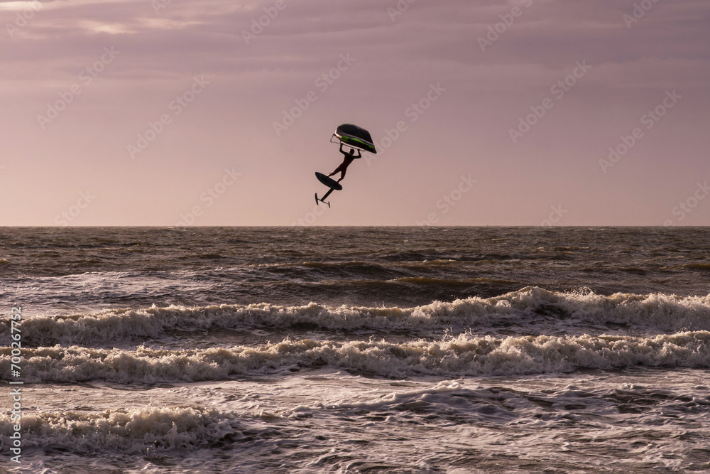 Silhouette of a person wingfoiling in the sea