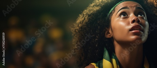 Anxious young Brazilian soccer fan, a black woman, holding Brazil flag, watching the match. © TheWaterMeloonProjec