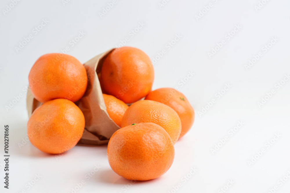 Group of tangerines in kraft paper bag.