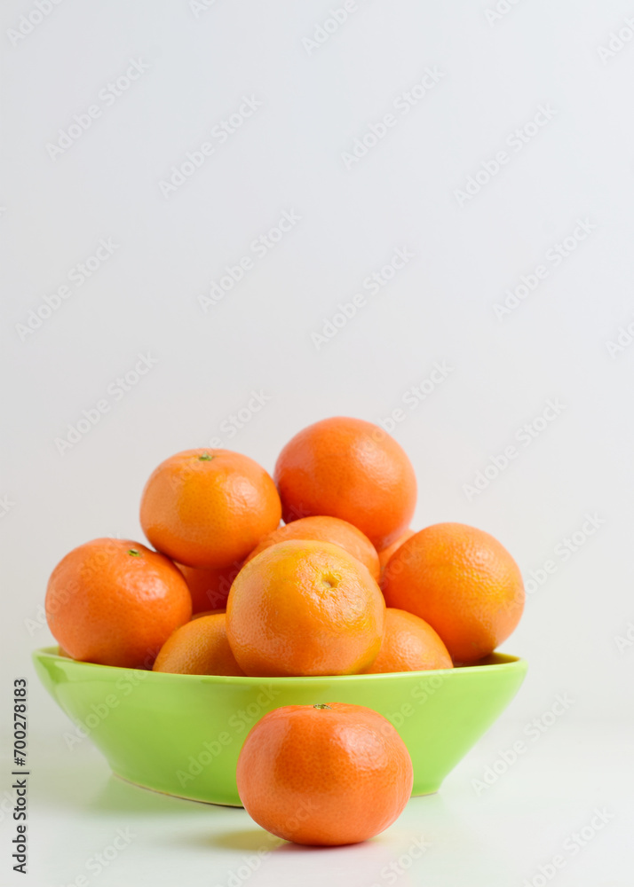 Close up. Tangerines on white background and green porcelain plate. Vertical shot and copy space.
