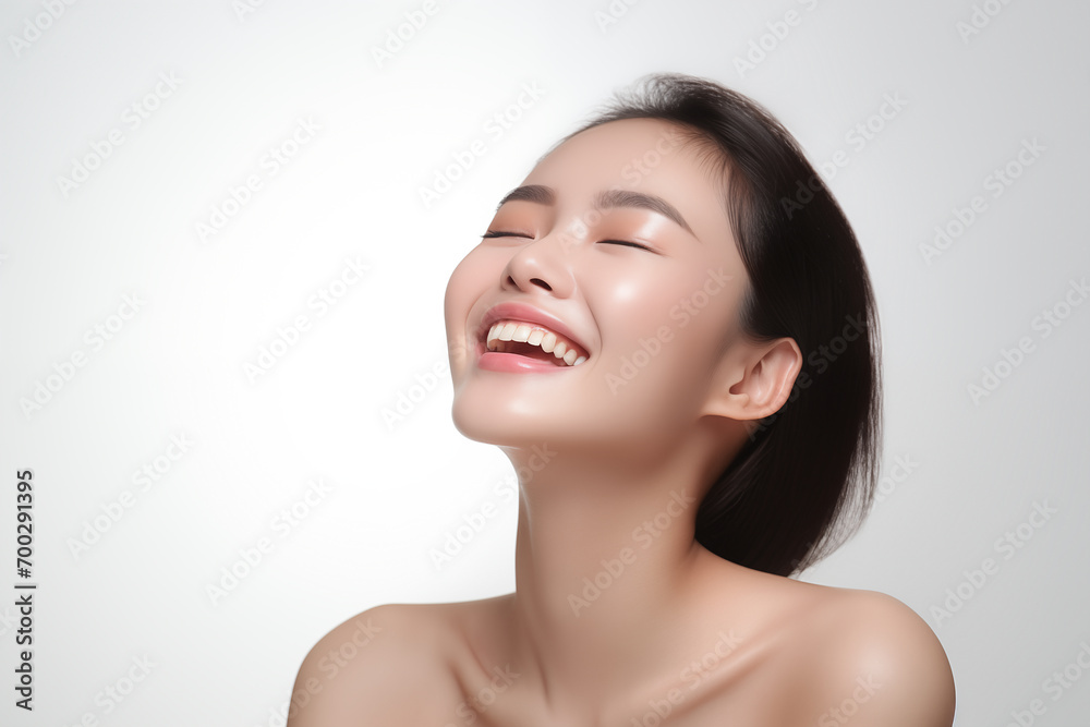 Beautiful laughing young Asian woman takes care of her skin, posing over grey background Beautiful laughing young Asian woman takes care of her skin, posing over grey background