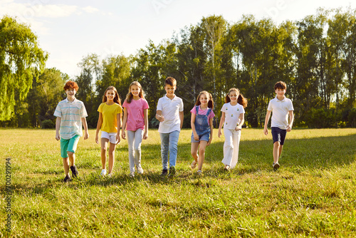 Happy children walking in a line together outside and smiling in the park on holidays enjoying spending time in a summer camp. Full length portrait of a kids having a walk in nature.