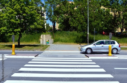 The car passes the pedestrian crossing with road from pedestrian refuge island