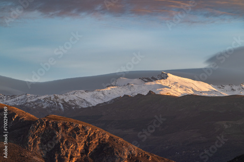 Sunset with spectacular lenticular clouds in the sky over the snowy peaks of Sierra Nevada (Granada, Spain)