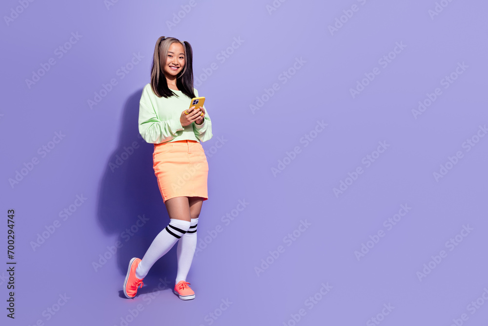 Full body length photo of japanese young student girl blogging using smartphone wear jumper mini skirt isolated on purple color background