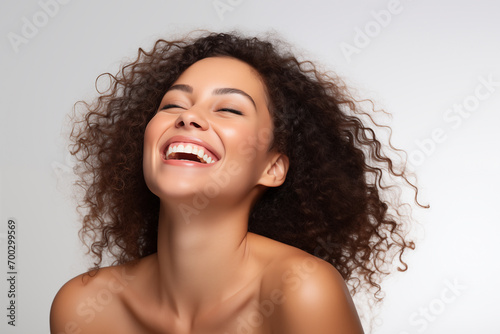 Beautiful happy Latin American woman takes care of her skin, posing over grey background photo