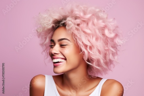 Portrait of a beautiful young woman with pink curly hair on a pink background