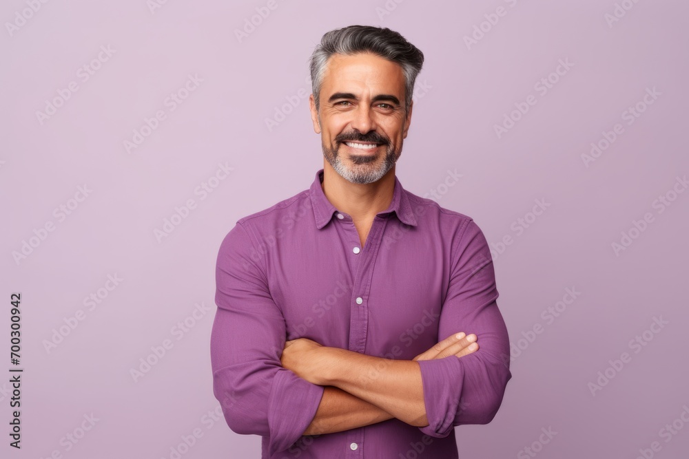 Portrait of handsome mature man with crossed arms looking at camera and smiling, standing against purple background Portrait of handsome mature man with crossed arms looking at camera and smiling, standing against purple background