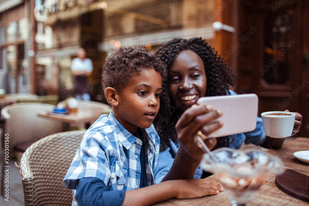 Mother and Son Enjoying a Video Call at an Outdoor Cafe Mother and Son Enjoying a Video Call at an Outdoor Cafe