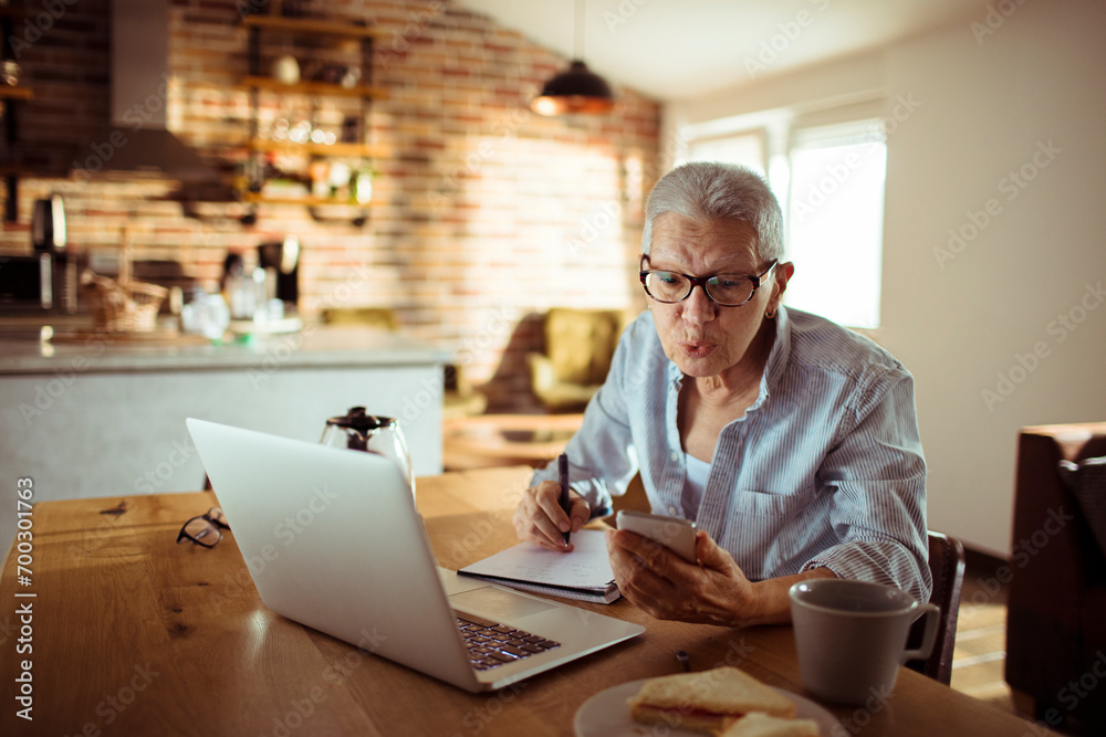 Senior woman working from home and taking notes Senior woman working from home and taking notes