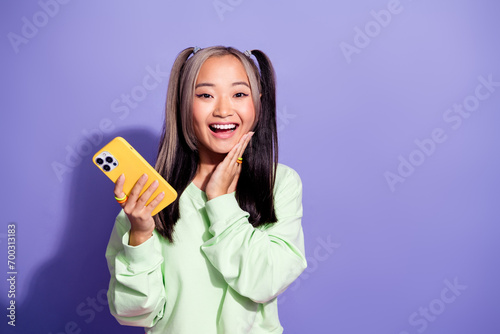 Photo of funky hipster youth girl wear pullover touch cheek amazed when boyfriend send message in phone isolated on purple color background