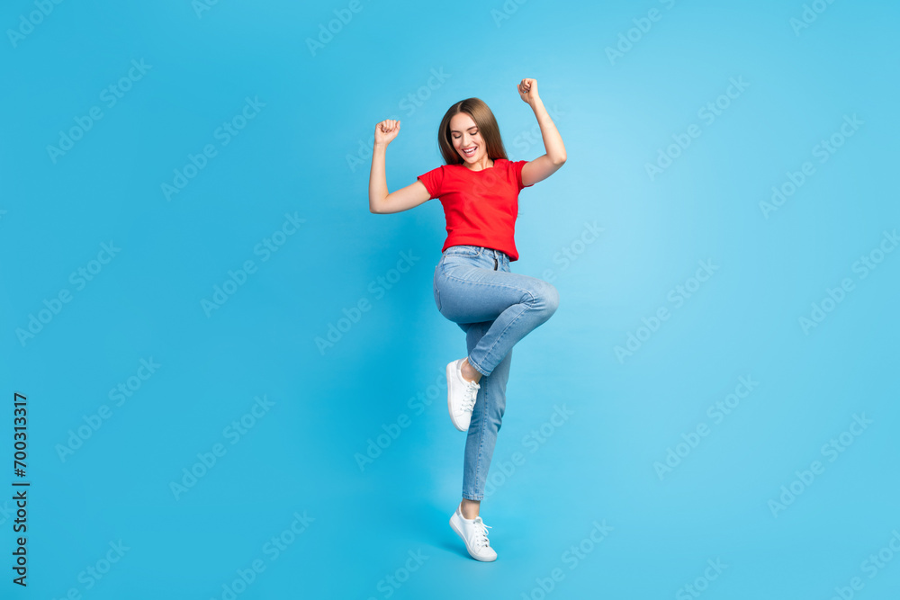 Full length photo of crazy cheerful girl dressed trendy clothes jumping with raised hands isolated on blue color background