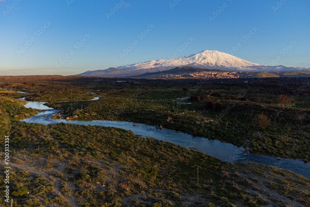 Bronte town under the snowy and majestic volcano Etna and a cloudy blue sky