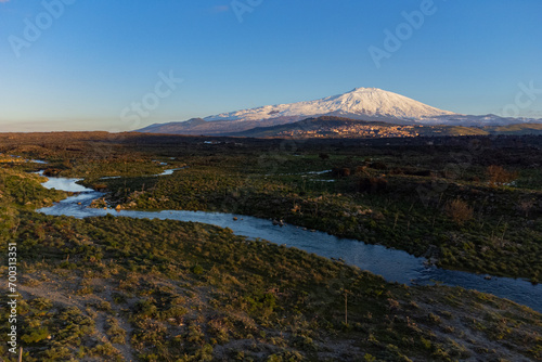 Bronte town under the snowy and majestic volcano Etna and a cloudy blue sky