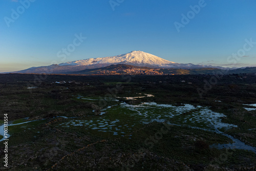 Bronte town under the snowy and majestic volcano Etna and a cloudy blue sky