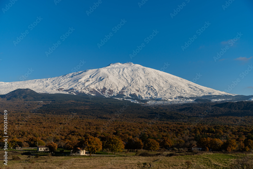 Bronte town under the snowy and majestic volcano Etna and a cloudy blue sky