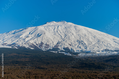 Bronte town under the snowy and majestic volcano Etna and a cloudy blue sky