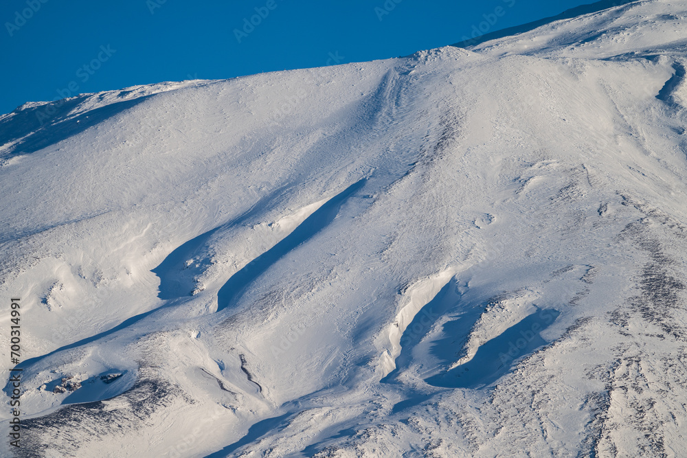 Bronte town under the snowy and majestic volcano Etna and a cloudy blue sky