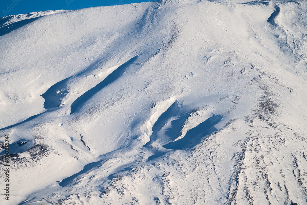 Bronte town under the snowy and majestic volcano Etna and a cloudy blue sky