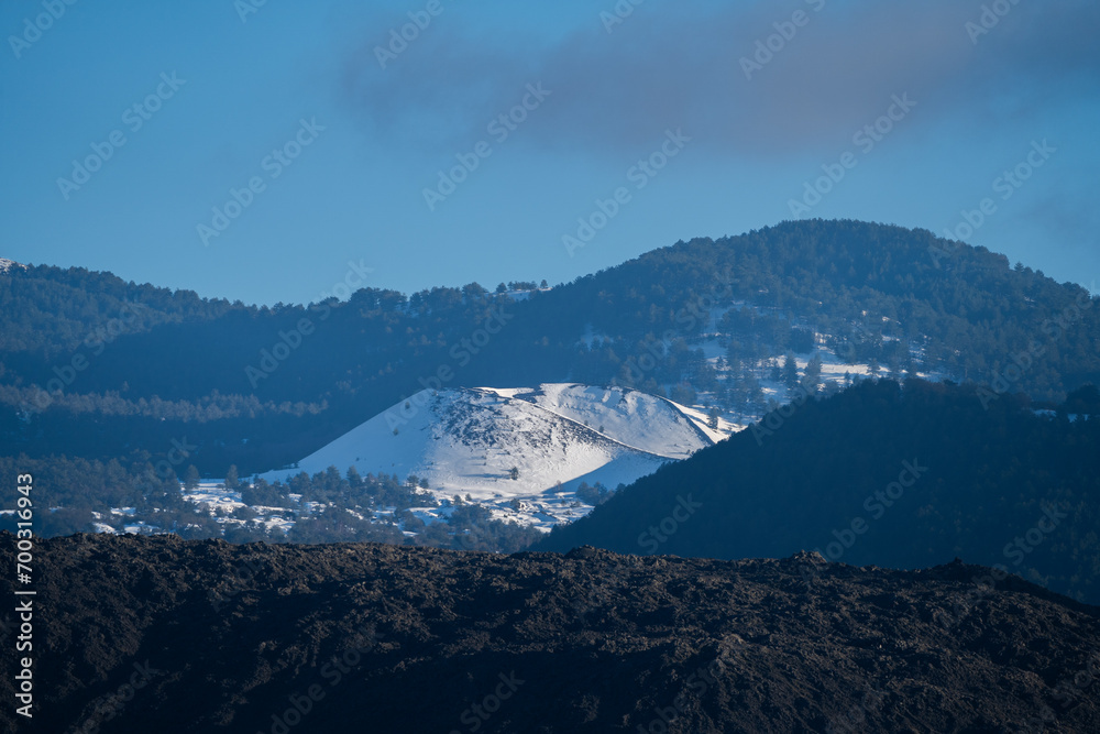 Bronte town under the snowy and majestic volcano Etna and a cloudy blue sky