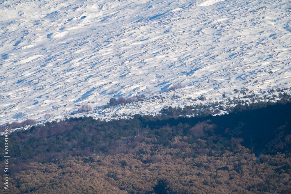 Bronte town under the snowy and majestic volcano Etna and a cloudy blue sky
