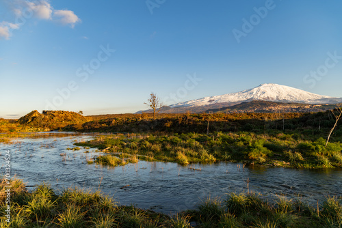 Obraz na płótnie A seasonal river flows under the massive snowcovered Etna volcano. Favare Santa Venera w salonie