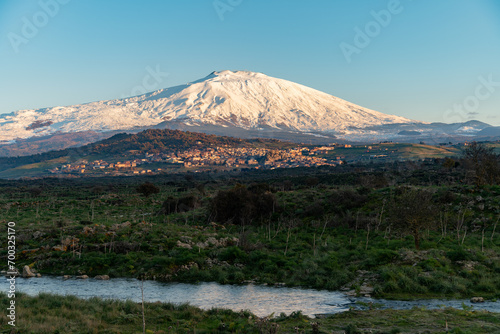 Bronte town under the snowy and majestic volcano Etna and a cloudy blue sky