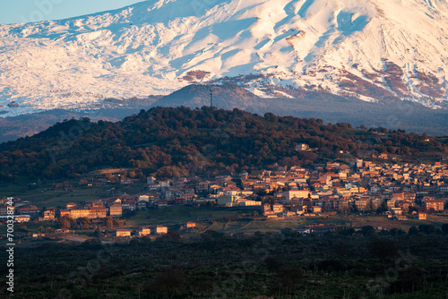 Bronte town under the snowy and majestic volcano Etna and a cloudy blue sky