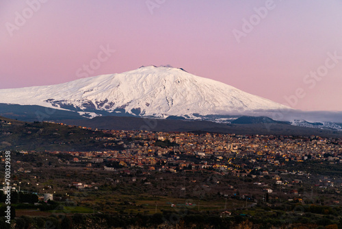 Bronte town under the snowy and majestic volcano Etna and a cloudy blue sky