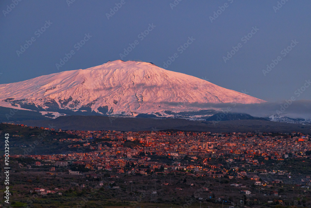 Bronte town under the snowy and majestic volcano Etna and a cloudy blue sky
