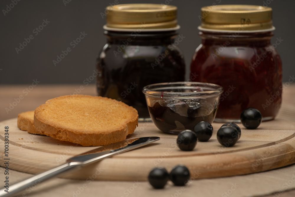 Blueberry jam on wooden plate with knife and bread. Made in Sicily