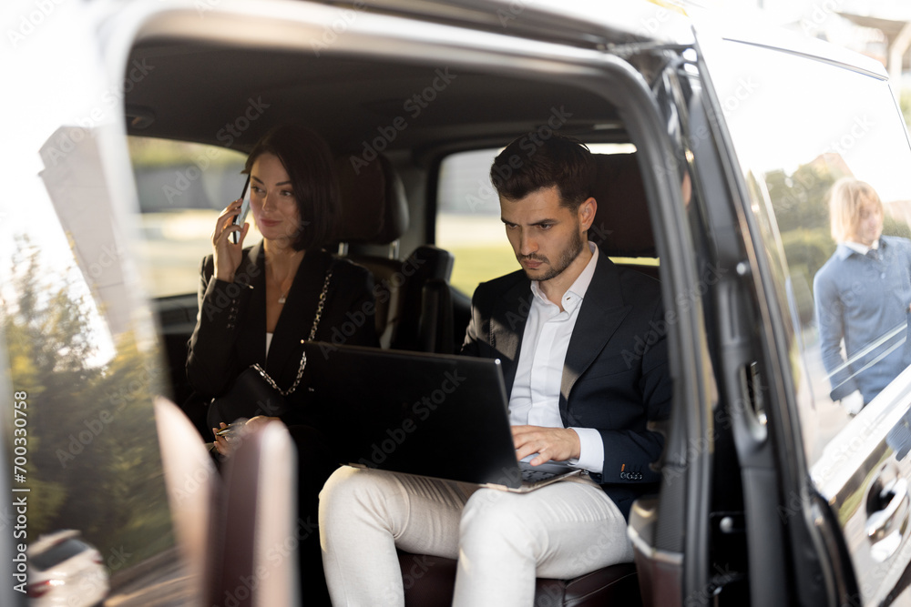 Business people sitting in minivan taxi, having some business, view through an open door. Concept of business trips and transportation