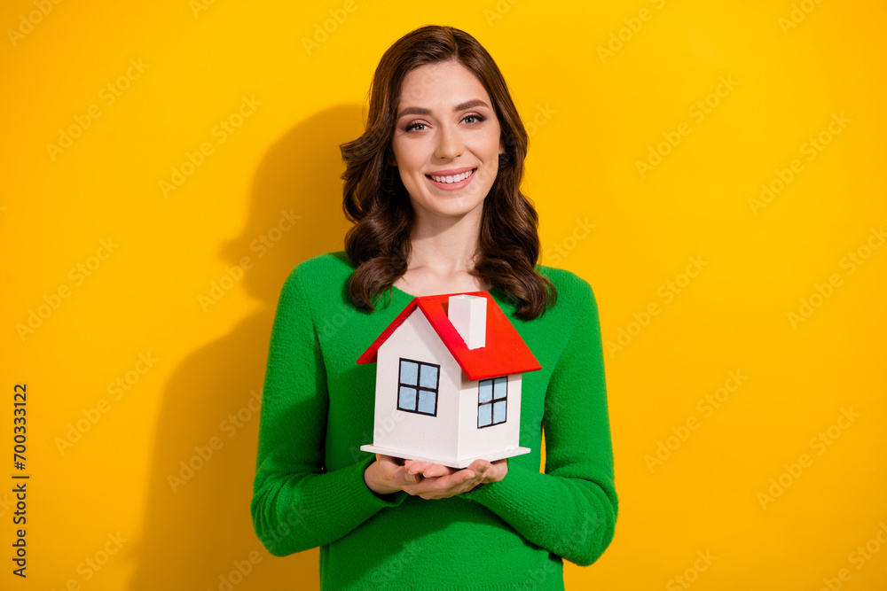 Photo of lovely woman wear stylish green clothes hold miniature house advertise buy cottage isolated on yellow color background Photo of lovely woman wear stylish green clothes hold miniature house advertise buy cottage isolated on yellow color background