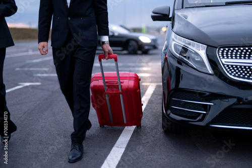 Quadro su tela Business couple walking with a suitcase on parking lot, arrived by luxury taxi