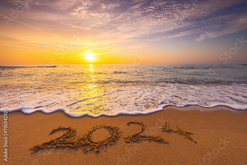 Happy New Year 2024 concept, lettering on the beach. Written text on the sea beach at sunrise.