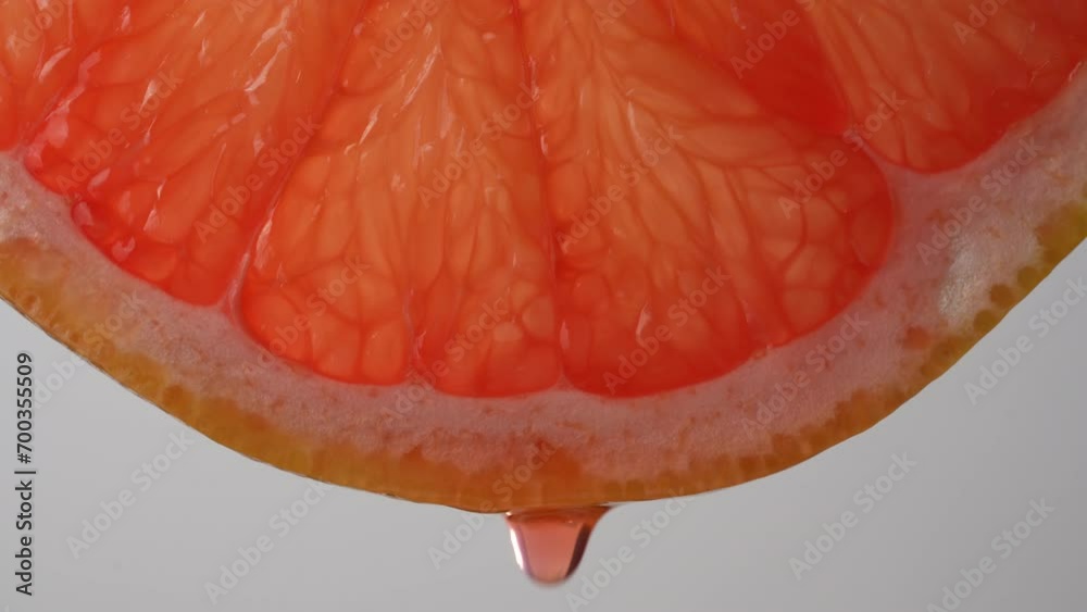 Slice of red grapefruit with juice drops on a white background, macro photography. Texture fresh citrus fruit, close up